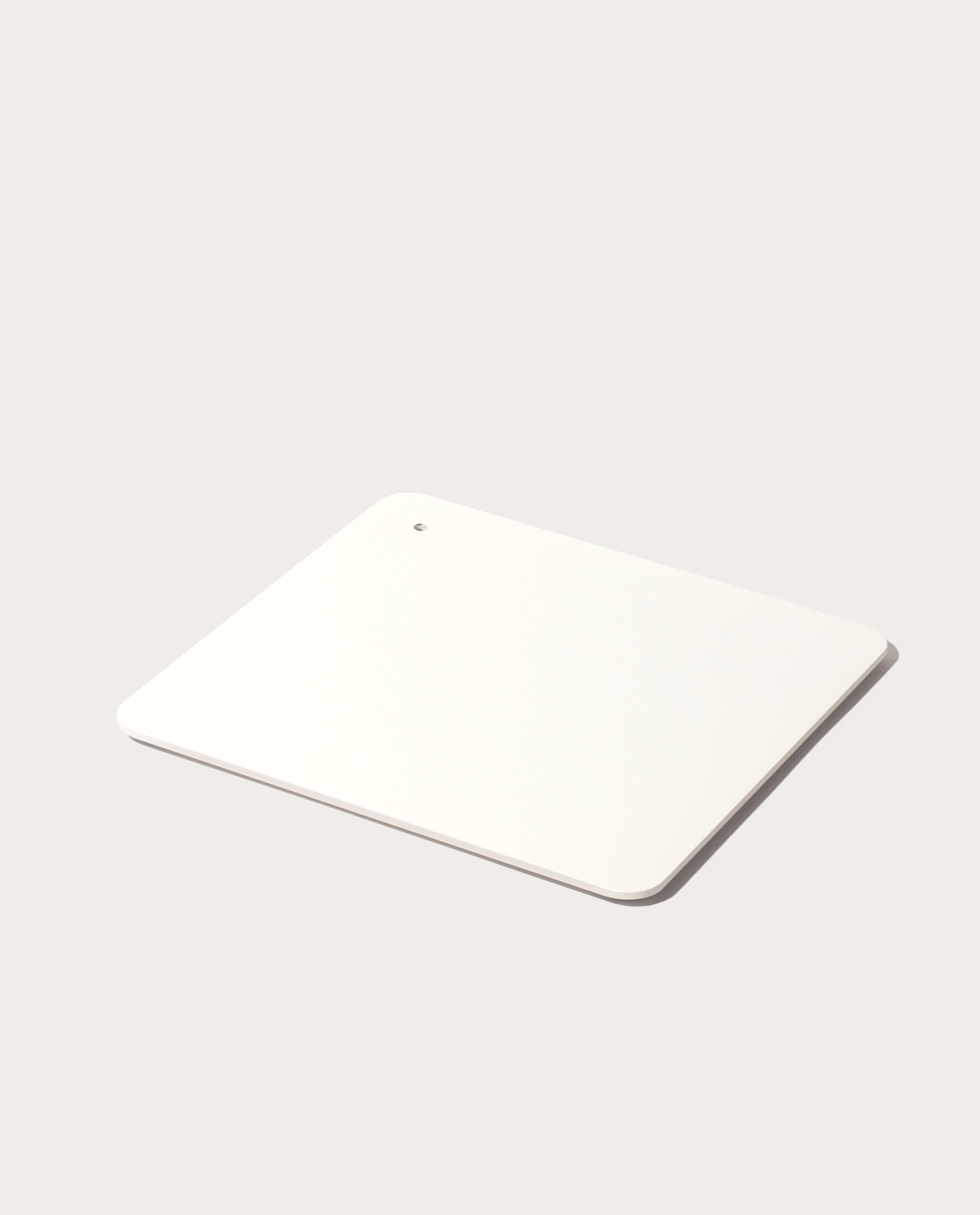 The minimalist white Gather 2x2 Base Plate with rounded corners and a small hole in one corner rests on a light gray surface, complementing the sleek magnetic Gather modules.