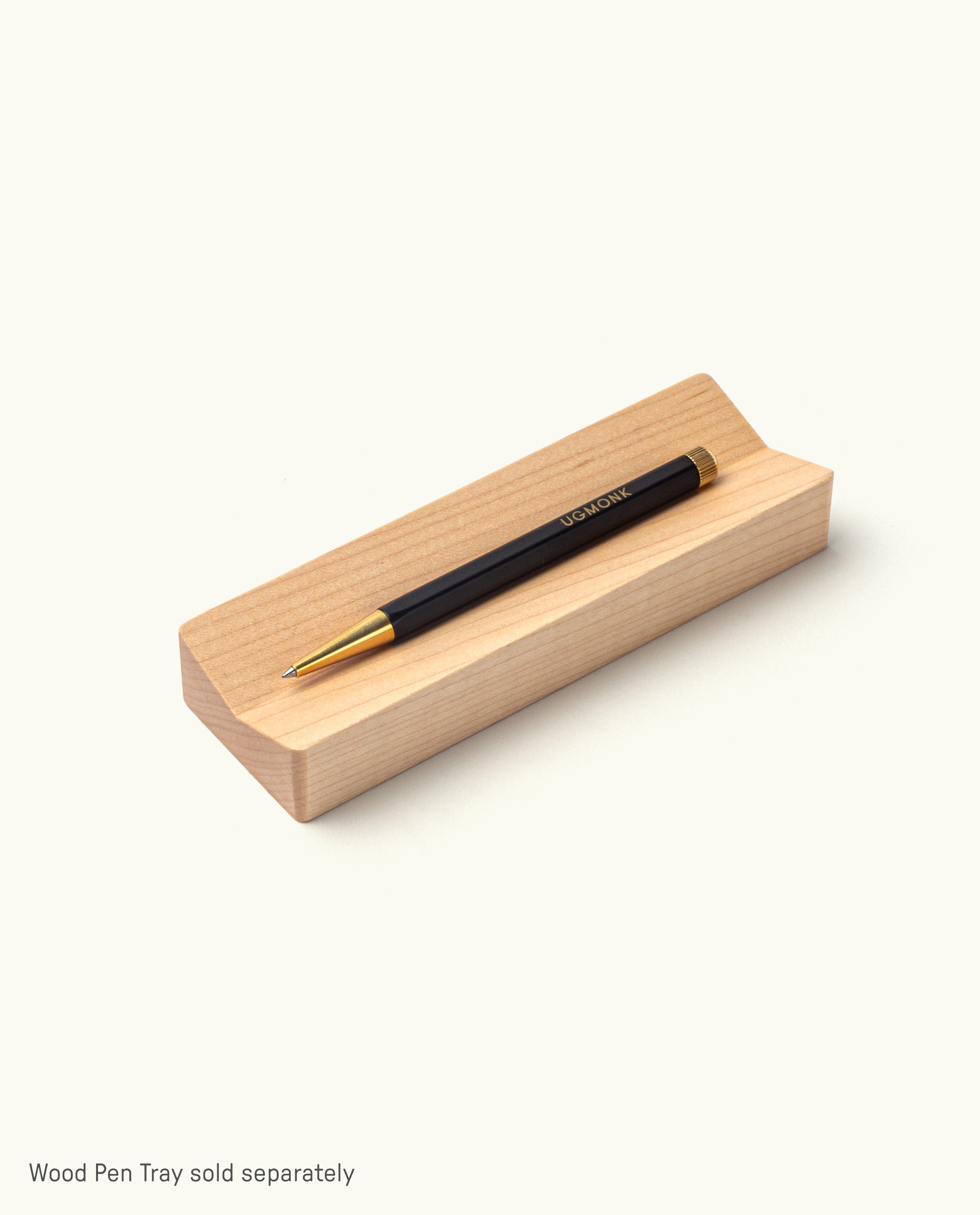 The Ugmonk Pen (Leuchtturm1917 Drehgriffel - Black) sits on a light wooden pen tray against a plain white background. Text below says, “Wood Pen Tray sold separately.”.