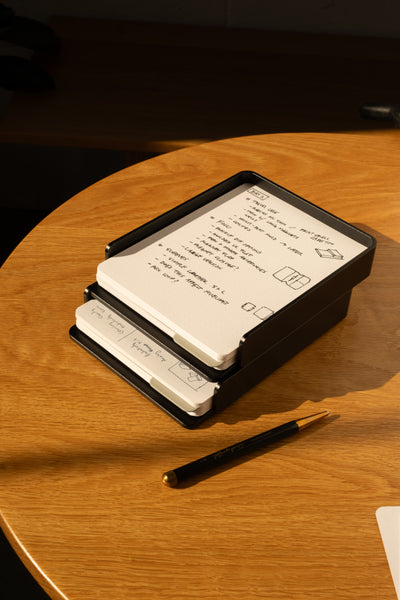 The Analog Capture Kit - 2 Large (Black Aluminum) features dot grid cards in a sleek black aluminum tray, with a pen nearby on a wooden table—everything you need to capture your ideas in style.