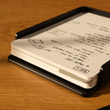 The Analog Capture Kit - Large (Black Aluminum) includes large dot grid cards in a sleek black holder, with a black pen featuring a gold tip, all resting on a wooden surface—an ideal setup for your notes.