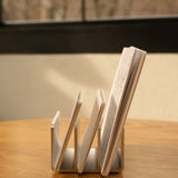 An Analog Card Organizer (Silver Aluminum) sits on a wooden table, neatly storing cards and papers, with a window and blurred outdoor scenery visible in the background.