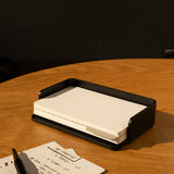 The Complete Analog Collection (Black Aluminum) sits on a wooden table with blank index cards in a sleek black organizer, beside a handwritten note and black pen as warm sunlight casts soft shadows over the scene.