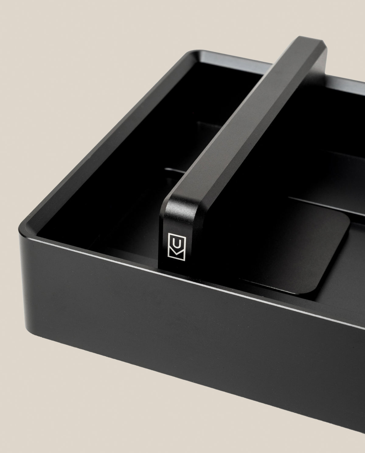An Analog Archive (Black Aluminum) desk organizer made of solid black aluminum with a central divider featuring a white U-shaped logo.