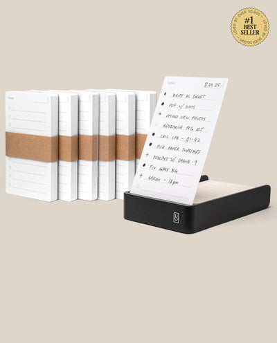 The Analog Daily Focus Kit + 6 Refills (Black Aluminum) includes a sleek black notepad base and six stacks of daily planner sheets with brown paper bands. A gold #1 Best Seller badge is displayed in the top right corner.