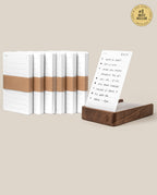 The Analog Daily Focus Kit + 6 Refills (Walnut) features white planner notepads with brown bands, standing upright beside a walnut card holder displaying a filled page. A gold “#1 Best Seller” badge highlights this analog productivity essential.