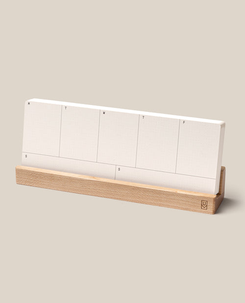 The Analog Weekly Planning Kit (Maple) features seven labeled Weekly Planner Cards—one for each day—displayed on a sleek maple stand against a simple beige background.