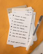 A close-up of a handwritten to-do list on premium Analog Trial Pack card stock, featuring photo shoot tasks and a pen, with other 3x5 cards partially visible underneath on an orange surface. The date 4.13.25 is at the top.