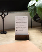 A set of Analog - Today Cards sits on a wooden stand atop a desk, accompanied by scissors, a plant, and a leather mat. The cards display tasks such as “Email Sara” and “Order prototypes,” demonstrating an effective productivity system for prioritizing daily tasks.