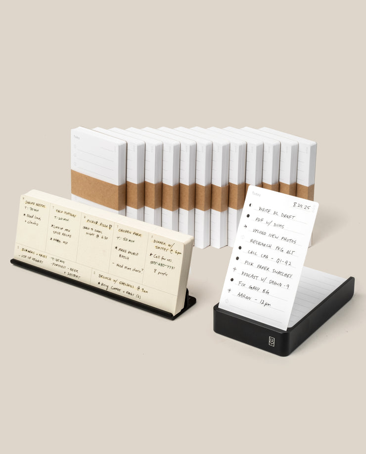 The Analog Annual Kit (Black Aluminum) is displayed with white lined notecards—some bound with brown paper bands—and features a black Weekly Card Holder and Daily Card Holder showcasing handwritten notes and a daily to-do list.