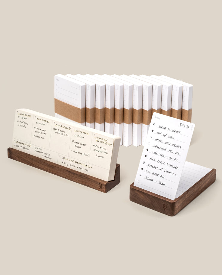 The Analog Annual Kit (Walnut) features white analog cards, some bound with brown bands, others displayed in walnut holders with handwritten notes, lists, and schedules—all set against a light beige background.