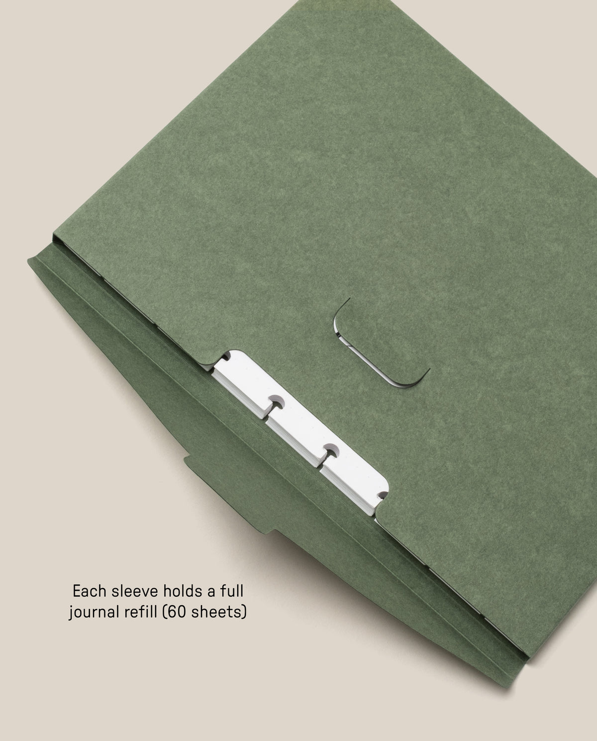A green Discbound Journal Archive with metal rings is open, revealing part of the inside. Text reads, Each sleeve holds a full journal refill (60 sheets), making it ideal for refillable journal sleeves and convenient journal storage.