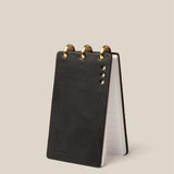 Black leather notepad with gold accents on a beige background