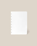 A Discbound Journal Refill - Blank (Standard 6″ x 8.5″) with seven disc bindings on the left side, designed for use with refill paper, is displayed upright against a plain beige background.