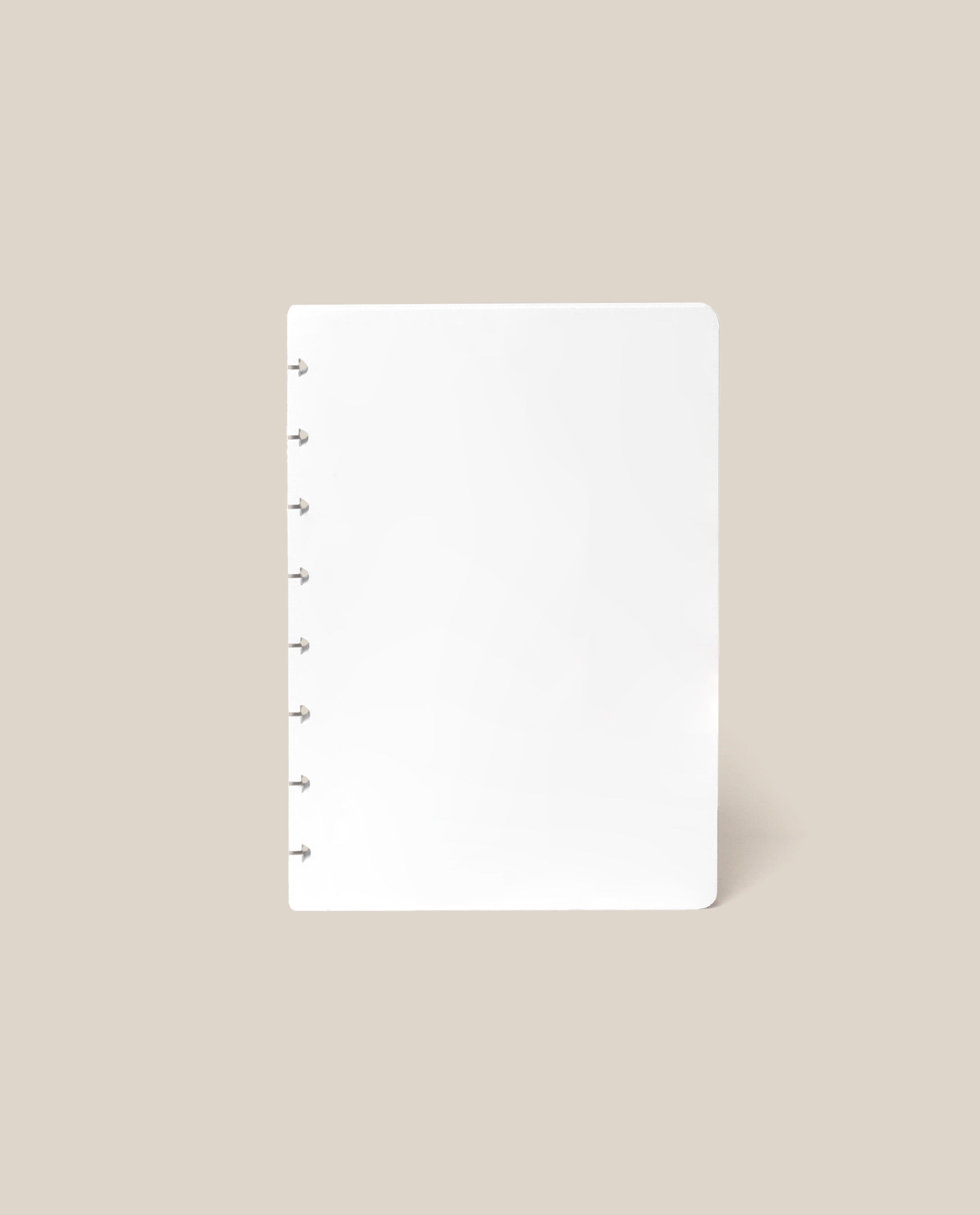 A Discbound Journal Refill - Blank (Standard 6″ x 8.5″) with seven disc bindings on the left side, designed for use with refill paper, is displayed upright against a plain beige background.