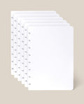 Five sheets of the Discbound Journal Refill - Blank (Standard 6″ x 8.5″), each crisp and white with rounded corners and a row of small arrow-shaped holes along the left edge—ideal for your Heirloom Discbound Journal—are fanned out against a light beige background.