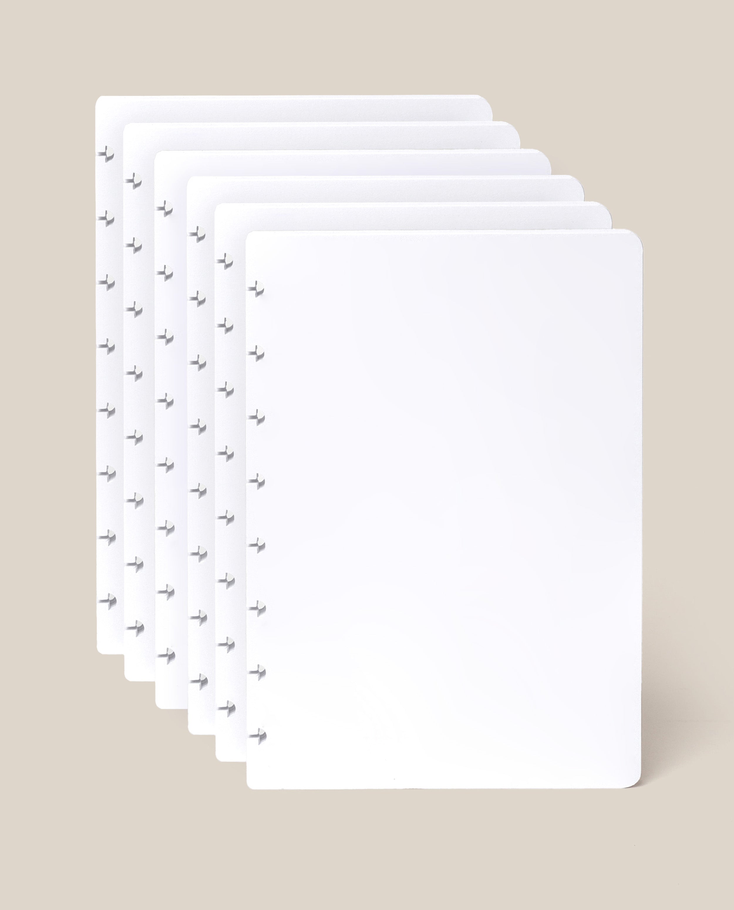 Five sheets of the Discbound Journal Refill - Blank (Standard 6″ x 8.5″), each crisp and white with rounded corners and a row of small arrow-shaped holes along the left edge—ideal for your Heirloom Discbound Journal—are fanned out against a light beige background.