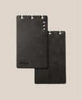 Two black leather card holders on a beige background