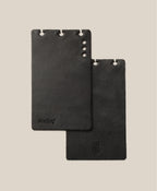 Two black leather card holders on a beige background