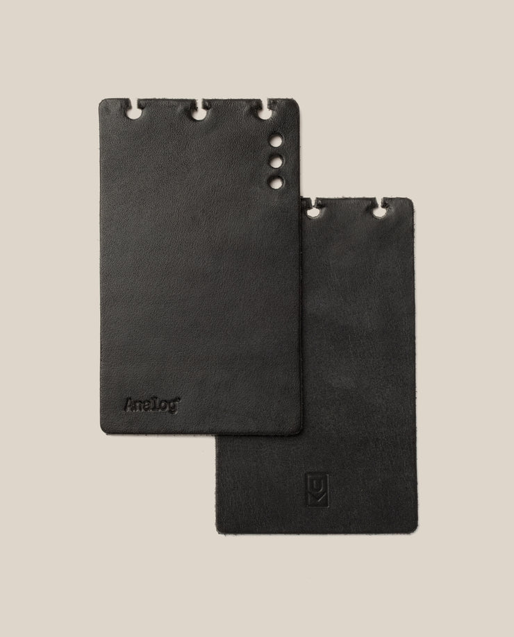 Two black leather card holders on a beige background