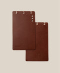 Two brown leather notebooks on a beige background