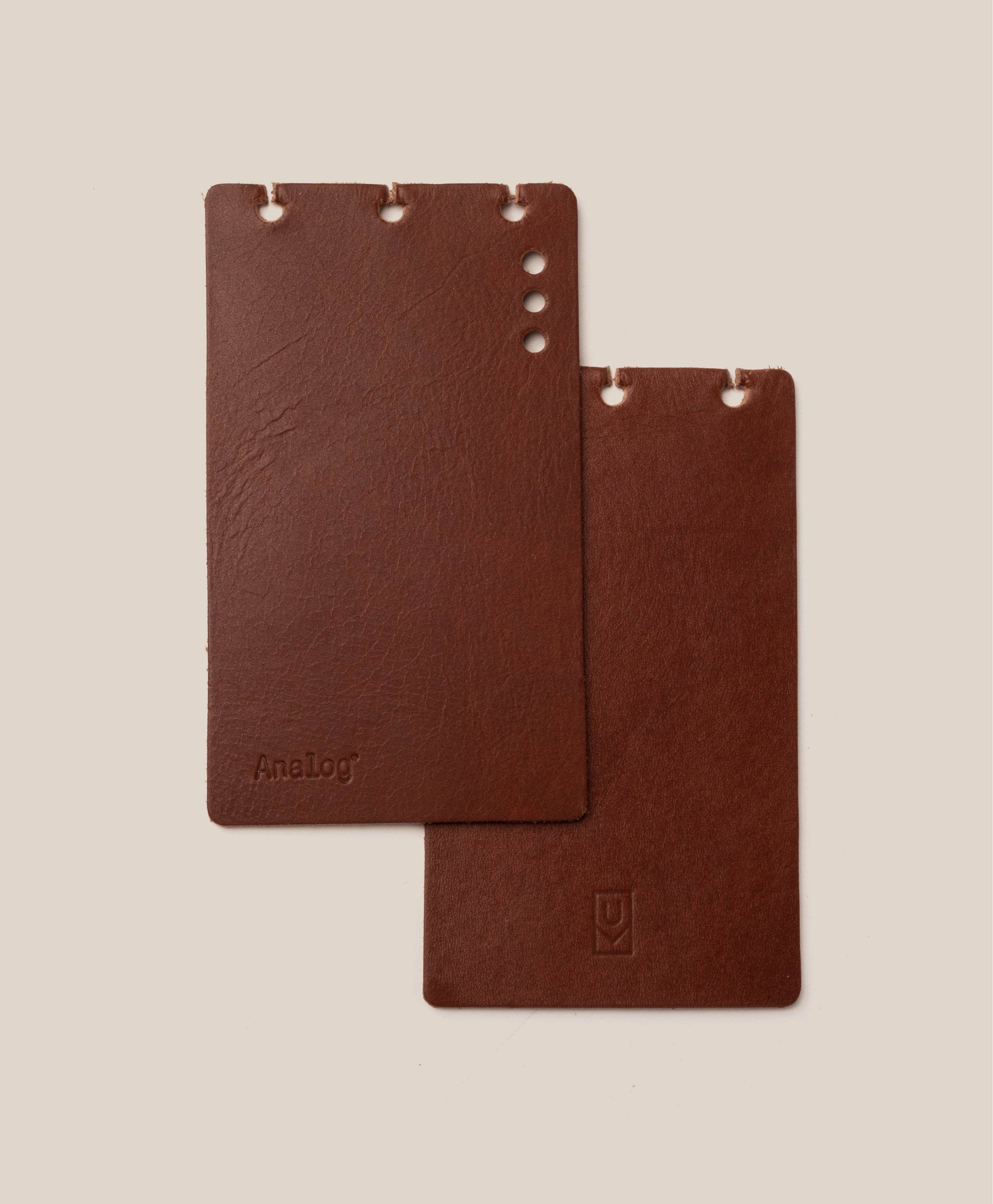 Two brown leather notebooks on a beige background