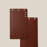 Two brown leather notebooks on a beige background