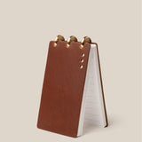 Brown leather notepad with gold accents on a beige background