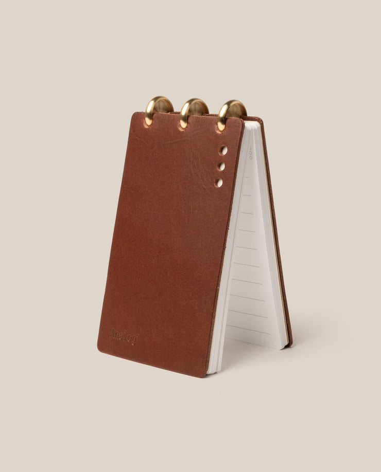 Brown leather notepad with gold accents on a beige background