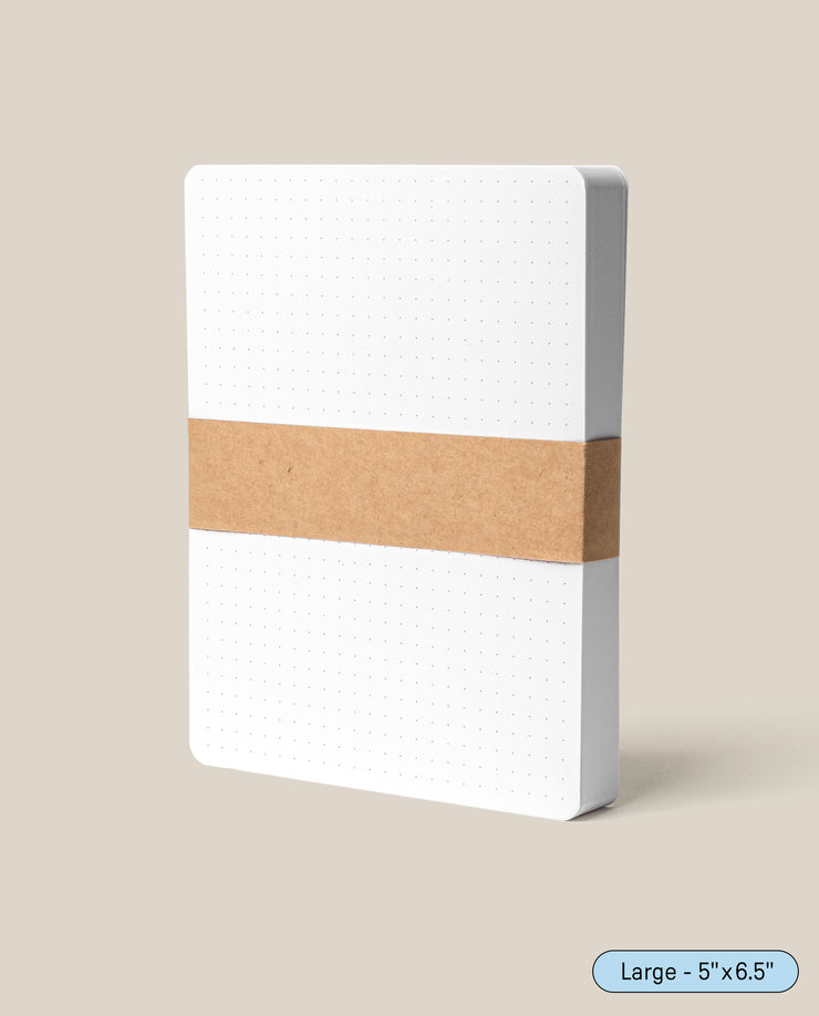 A pack of Analog Dot Grid Cards - Large (1-Pack), featuring white premium card stock with a dot grid and rounded corners, is wrapped in a brown kraft paper band and displayed upright on a beige background. Label reads “Large – 5x6.5.”.