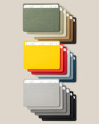 Eighteen Analog Card Sleeve Multipack - Large cardholders, each neatly securing two white cards inside protective Analog Card Sleeves, are arranged in three rows on a beige background. The top row showcases earth tones, the middle row displays vibrant colors, and the bottom row features grayscale shades—creating an organized and visually striking presentation of this stylish card organizer system.