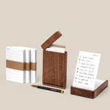 The Analog Complete Kit (Walnut) features a walnut desktop card holder with white notecards—some stacked, some displayed—a sleek black and gold refillable gel pen, and a light beige background. A notecard displays handwritten notes.