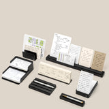 The Complete Analog Collection (Black Aluminum) is neatly arranged on black holders and trays against a beige background, showcasing organized notes and diagrams with a sleek desktop organizer.