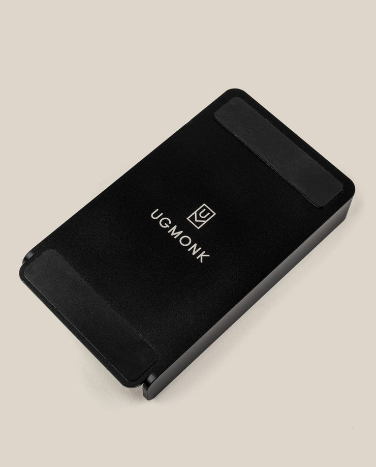 A sleek black rectangular Aluminum Card Holder with rounded edges, featuring the UGMONK logo and name in white, is part of the Analog Daily Focus Kit + 6 Refills (Black Aluminum). Photographed on a plain light beige background.
