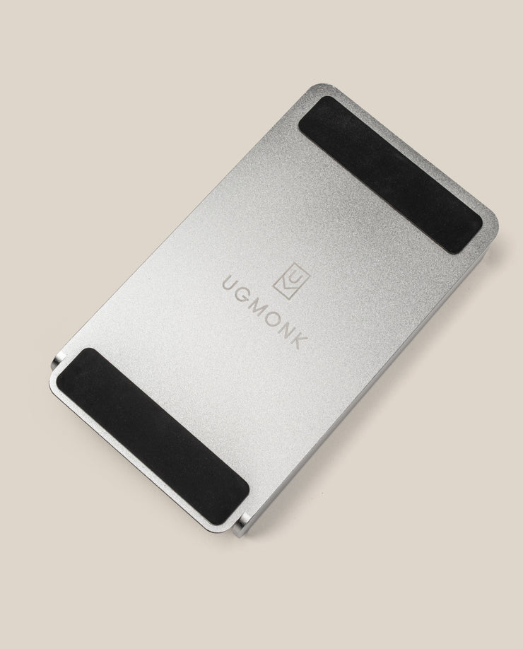 The Analog Annual Kit (Silver Aluminum) features a sleek rectangular metal stand with two black grips and "UGMONK" engraved in the center, ideal as a Weekly Card Holder, shown on a beige background.