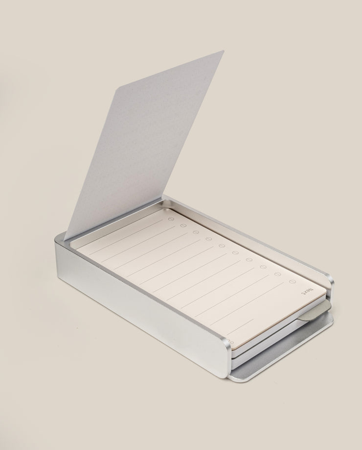 The Analog Daily Focus Kit + 6 Refills (Silver Aluminum) features a sleek, hinged aluminum card holder with lined task cards for notes and checkboxes—an elegant productivity tool displayed on a light beige surface.