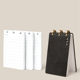 The Leather Discbound Analog + 3 Refills (Black) stands upright beside three stacks of “Today” daily planner pages with lines for notes and times, all displayed on a beige background—ideal for organization.