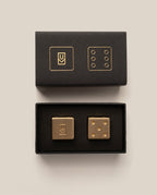Gold dice set with black boxes on a beige background