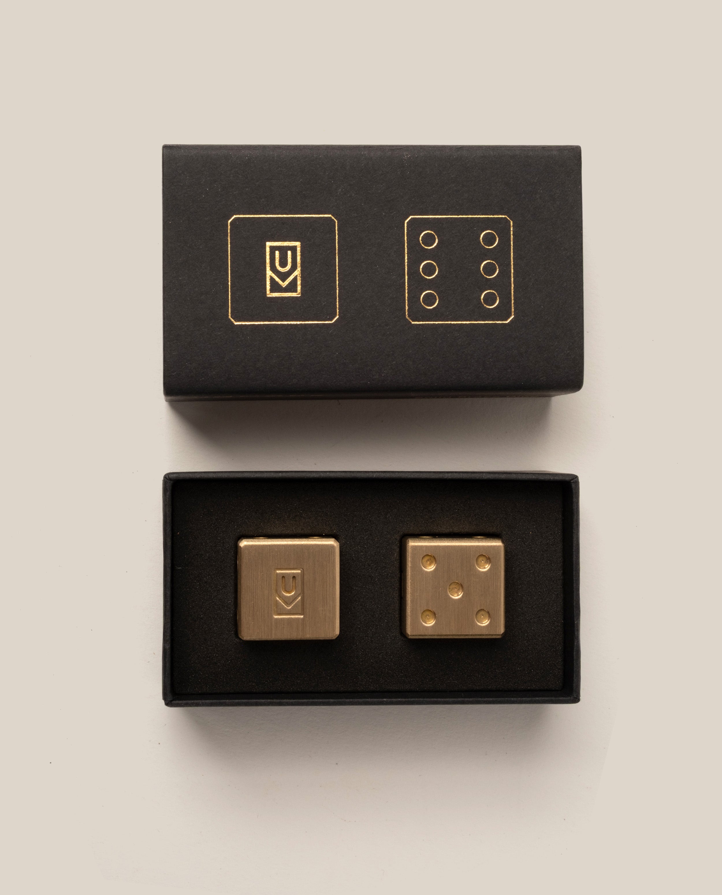 Gold dice set with black boxes on a beige background