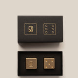Gold dice set with black boxes on a beige background