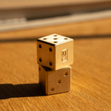 Two gold dice stacked on a wooden surface