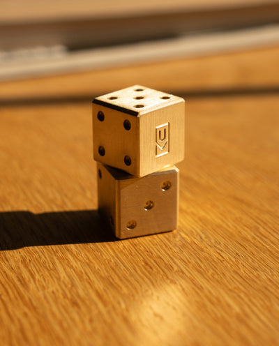 Two gold dice stacked on a wooden surface