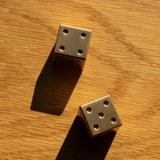 Two gold dice on a wooden surface