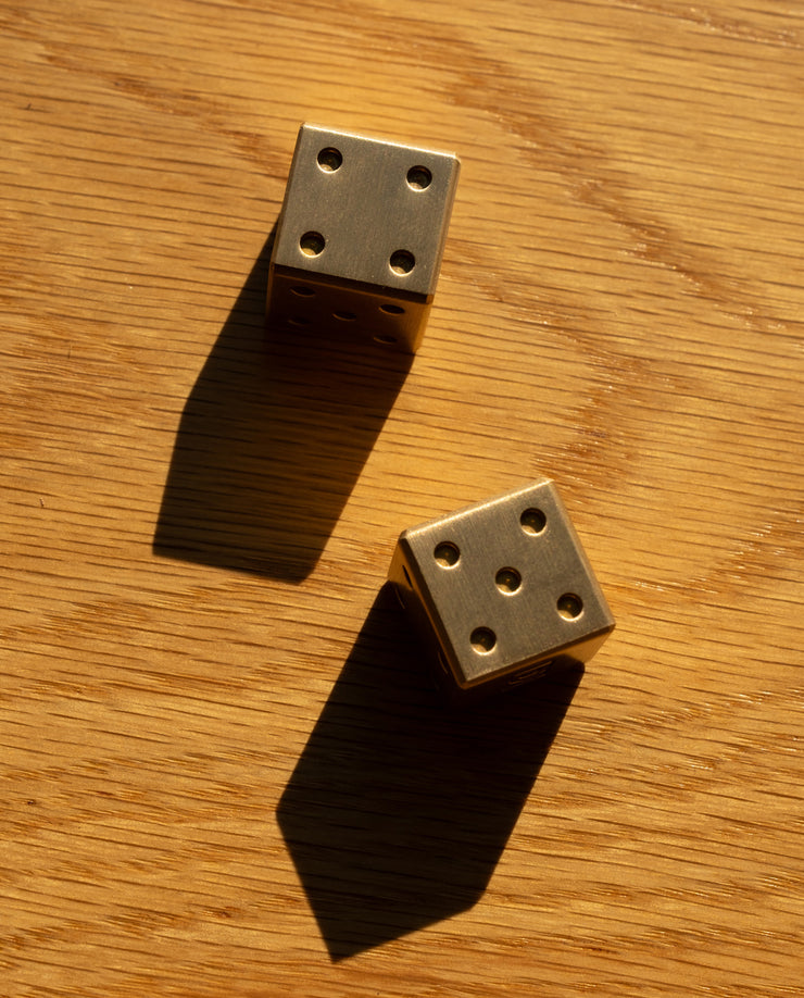 Two gold dice on a wooden surface