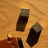 Two metallic dice and a leather case with a pen on a wooden surface