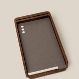 The Analog Daily Focus Kit (Walnut) features a wood card holder displaying dark gray analog task cards with three white dots, organized by a labeled divider for new and used cards, creating a simple productivity system on a light beige background.