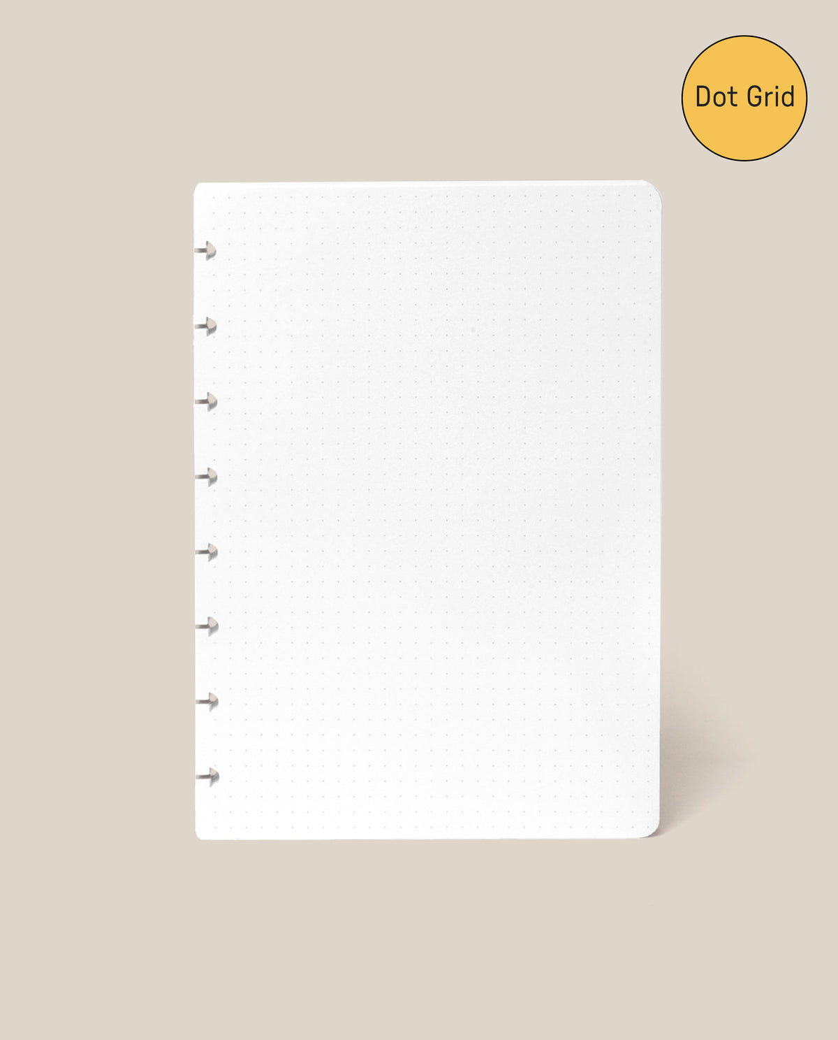 A white Discbound Journal Refill - Dot Grid (Standard 6″ x 8.5″) sheet featuring six disc-bound holes on the left is displayed against a beige background. In the top right corner, a yellow circle labeled “Dot Grid” highlights this as the ideal refill pack for your Heirloom Discbound Journal.