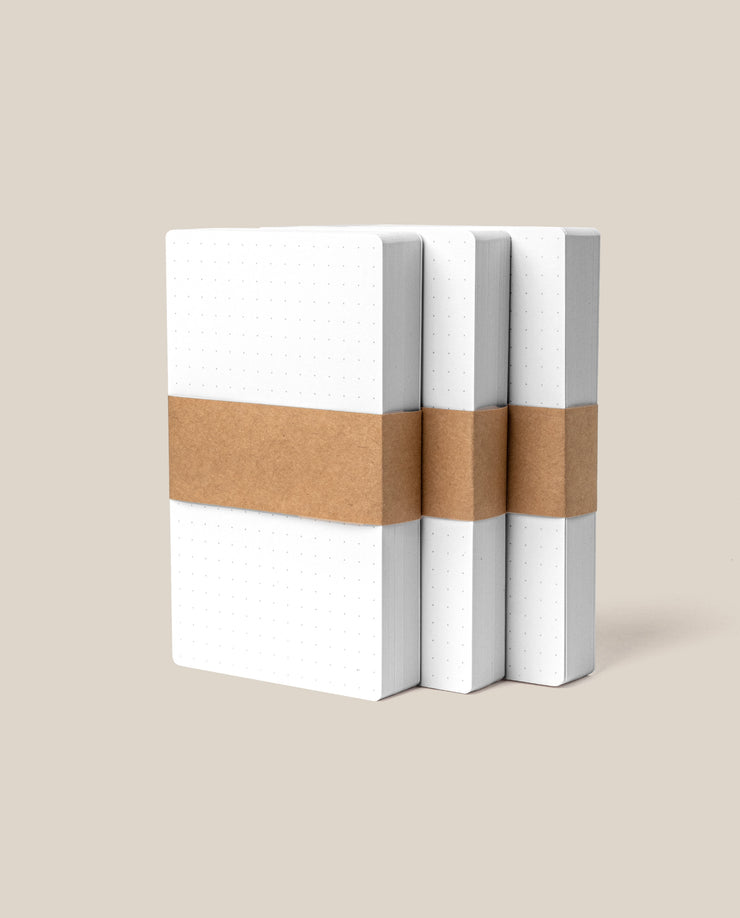 Three packs of Analog Dot Grid Cards - Small are displayed upright side by side, each set wrapped with a single brown paper band around the middle, against a plain beige background.