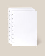Three sheets of white, dot grid paper with rounded corners are stacked slightly offset on a beige background. The left side of each sheet features several small disc-binding holes, making them perfect as the Discbound Journal Refill - Dot Grid (Standard 6″ x 8.5″) for your Heirloom Discbound Journal or as part of a convenient journal refill pack.