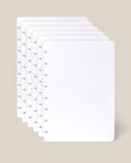 Six sheets of the Discbound Journal Refill - Dot Grid (Standard 6″ x 8.5″) with rounded corners are slightly fanned out against a light beige background, perfect for adding to your Heirloom Discbound Journal.