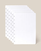 Six sheets of the Discbound Journal Refill - Dot Grid (Standard 6″ x 8.5″) with rounded corners are slightly fanned out against a light beige background, perfect for adding to your Heirloom Discbound Journal.